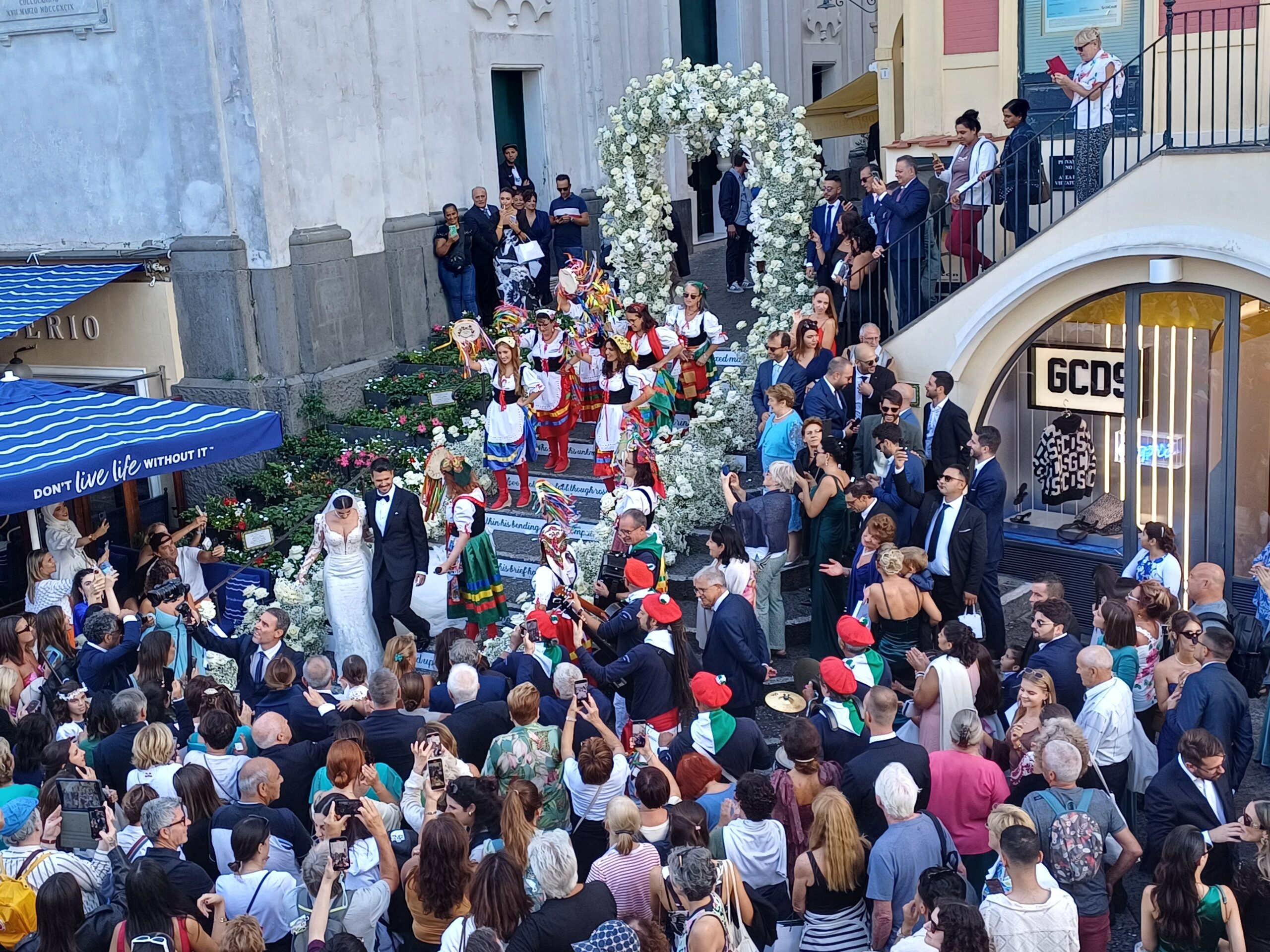 Scene da un matrimonio nella Piazzetta di Capri: Viviana e Simone sposi tra un arco di nozze e il sonetto di Shakespeare